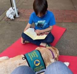 Child reading with dog